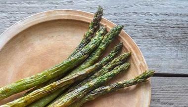 Roasted asparagus on a wooden plate.